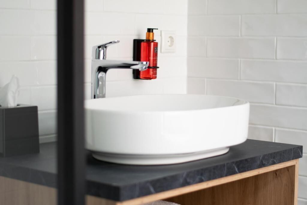 A white sink with a modern faucet, a soap dispenser, and a marble countertop.