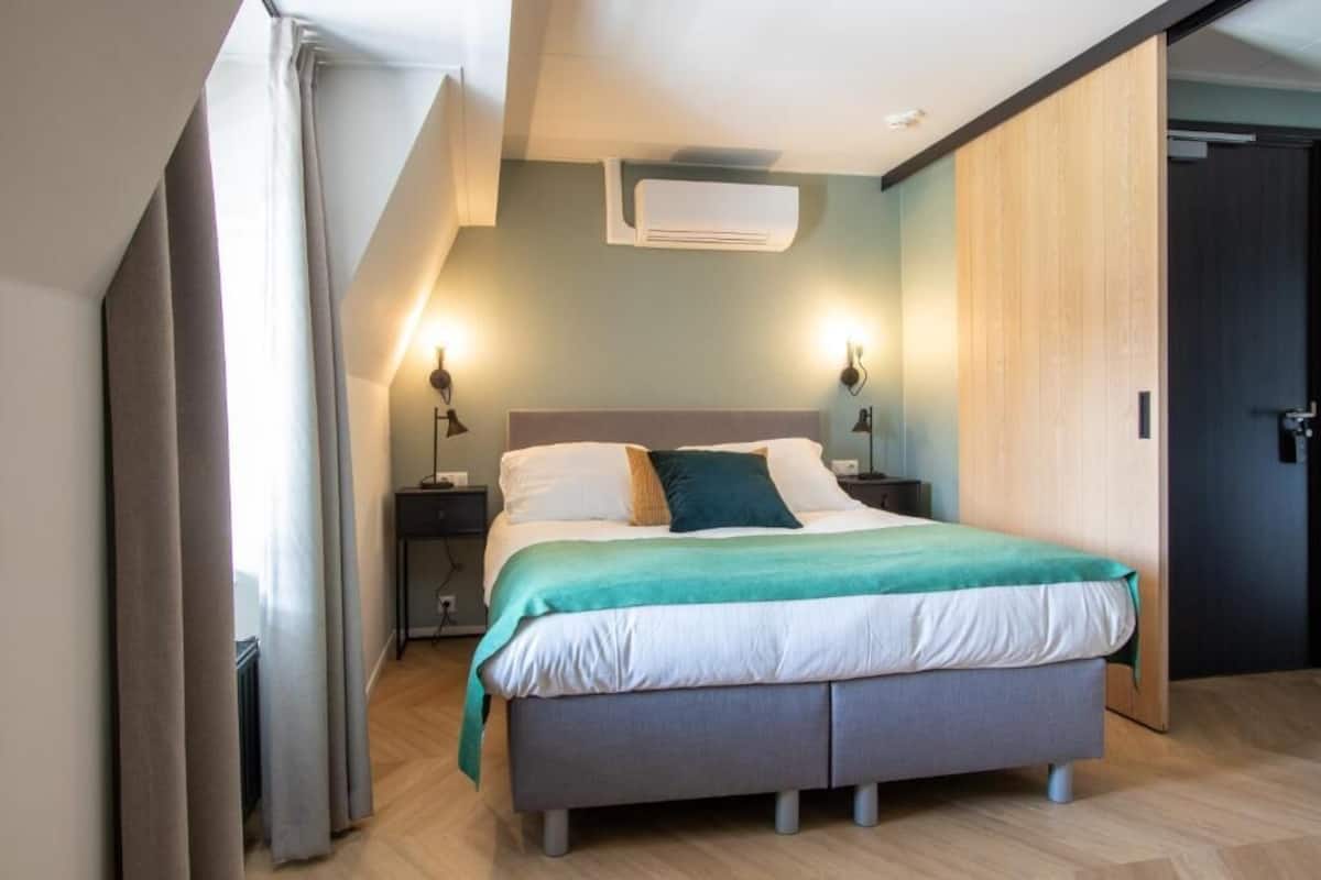 Ein modernes Schlafzimmer mit einem Bett, Nachttischlampen, einer Klimaanlage und einem Holzschrank.