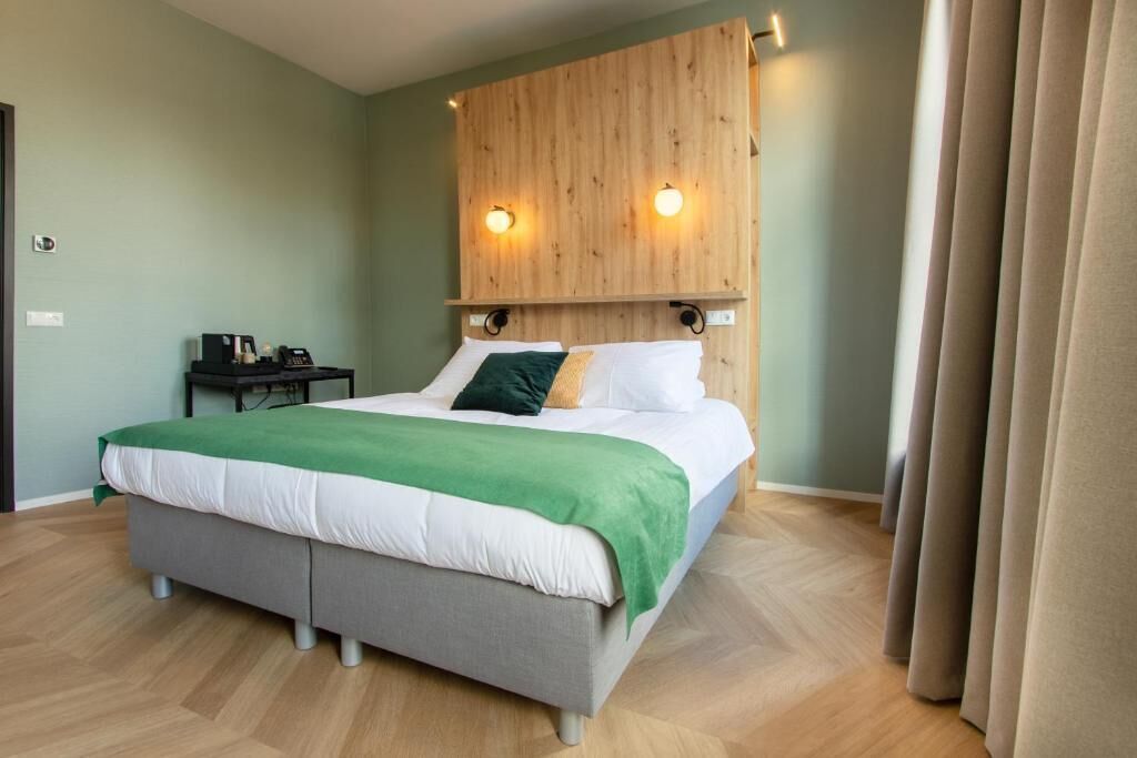 Un dormitorio moderno con cama, mesita de noche y cabecero de madera con luces fijadas a la pared.