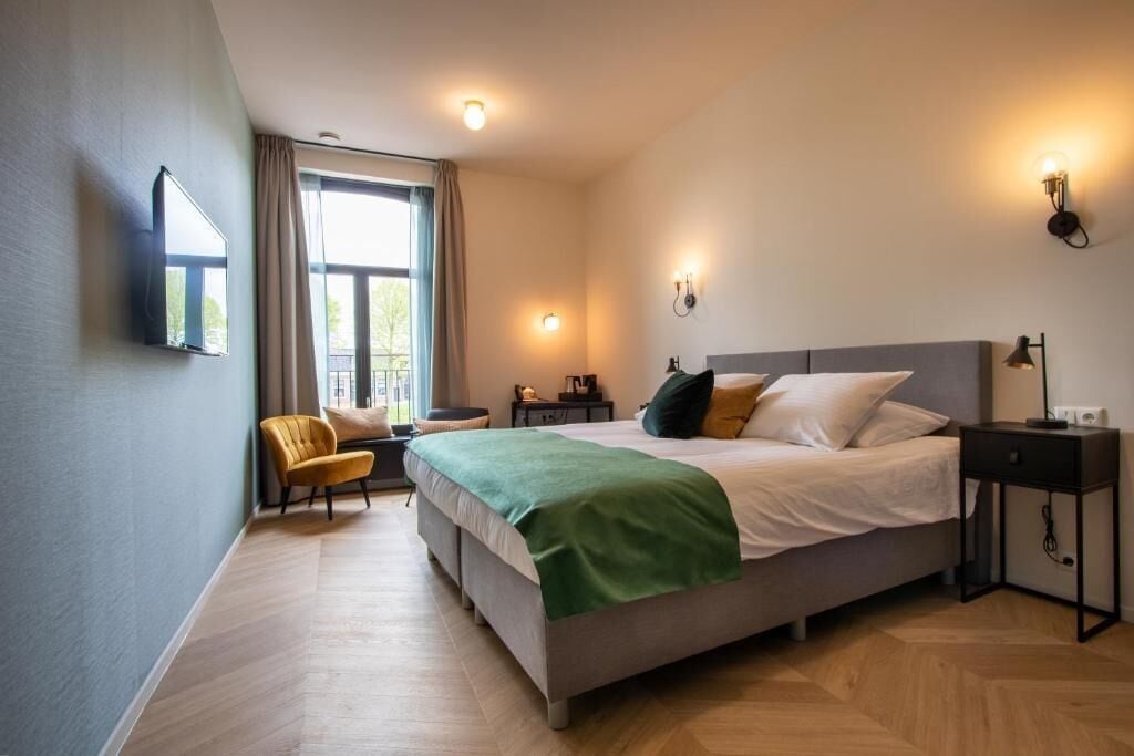 Une chambre à coucher avec un lit, des tables de chevet, une chaise et une fenêtre.