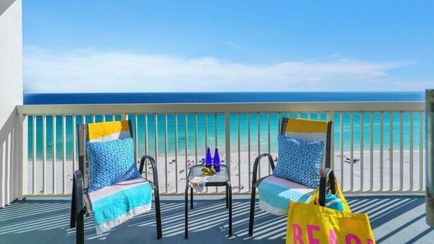 Ein Balkon mit zwei Stühlen, einem kleinen Tisch und Blick auf den Strand.