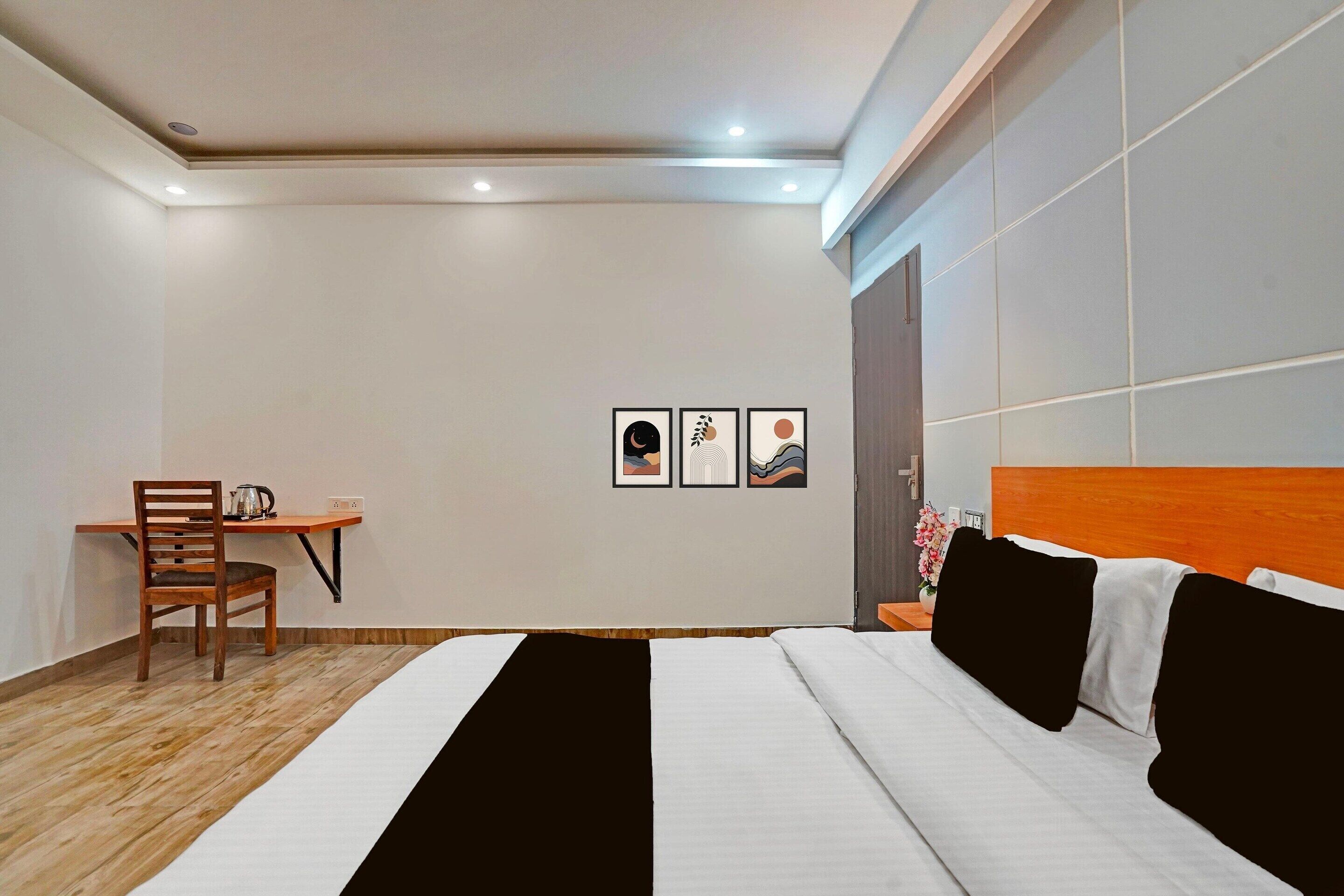 Een hotelkamer met een bed, een bureau en een stoel. Drie ingekaderde foto's hangen aan de muur.