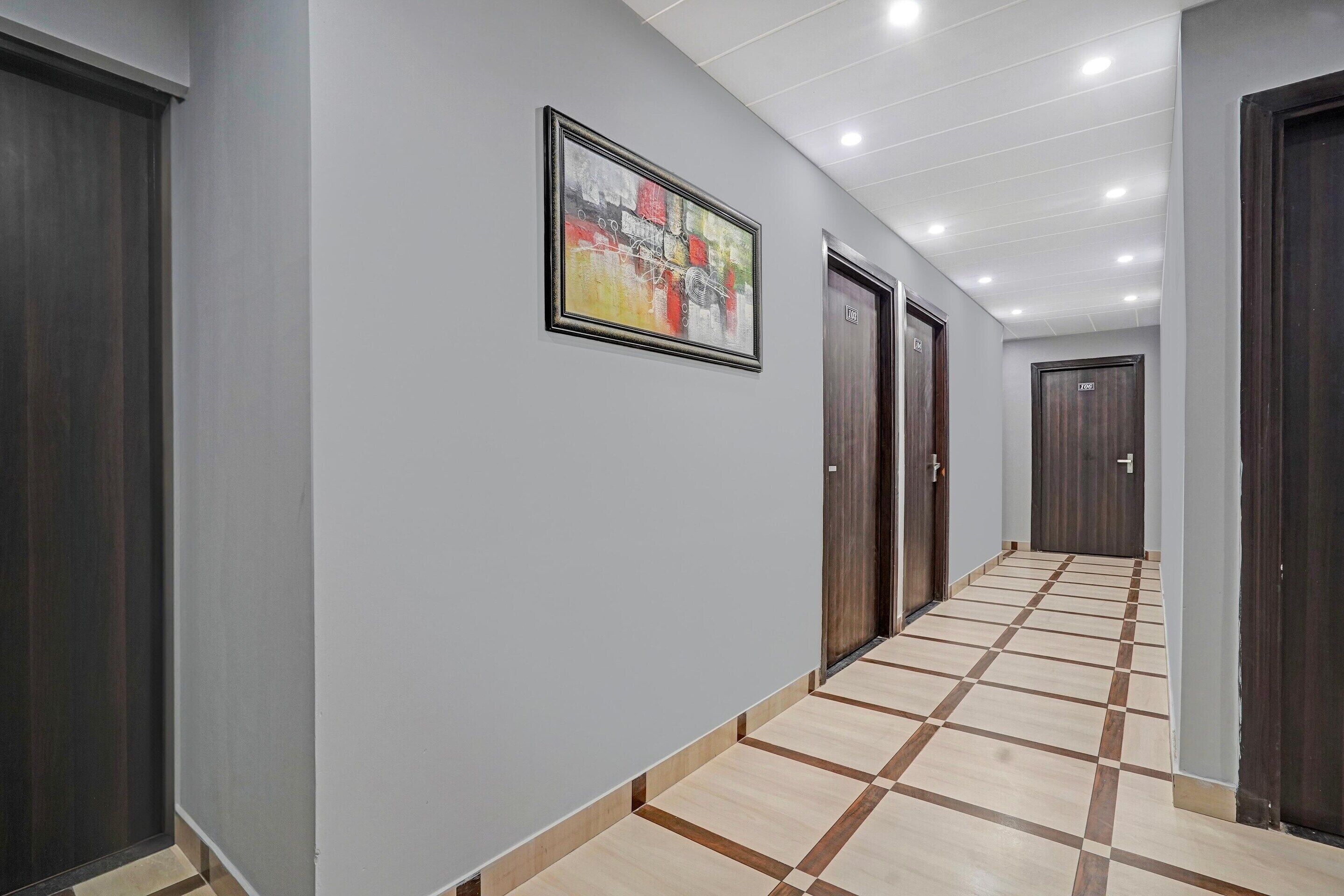 A hallway with a checkered floor, a framed abstract painting, and dark wooden doors.
