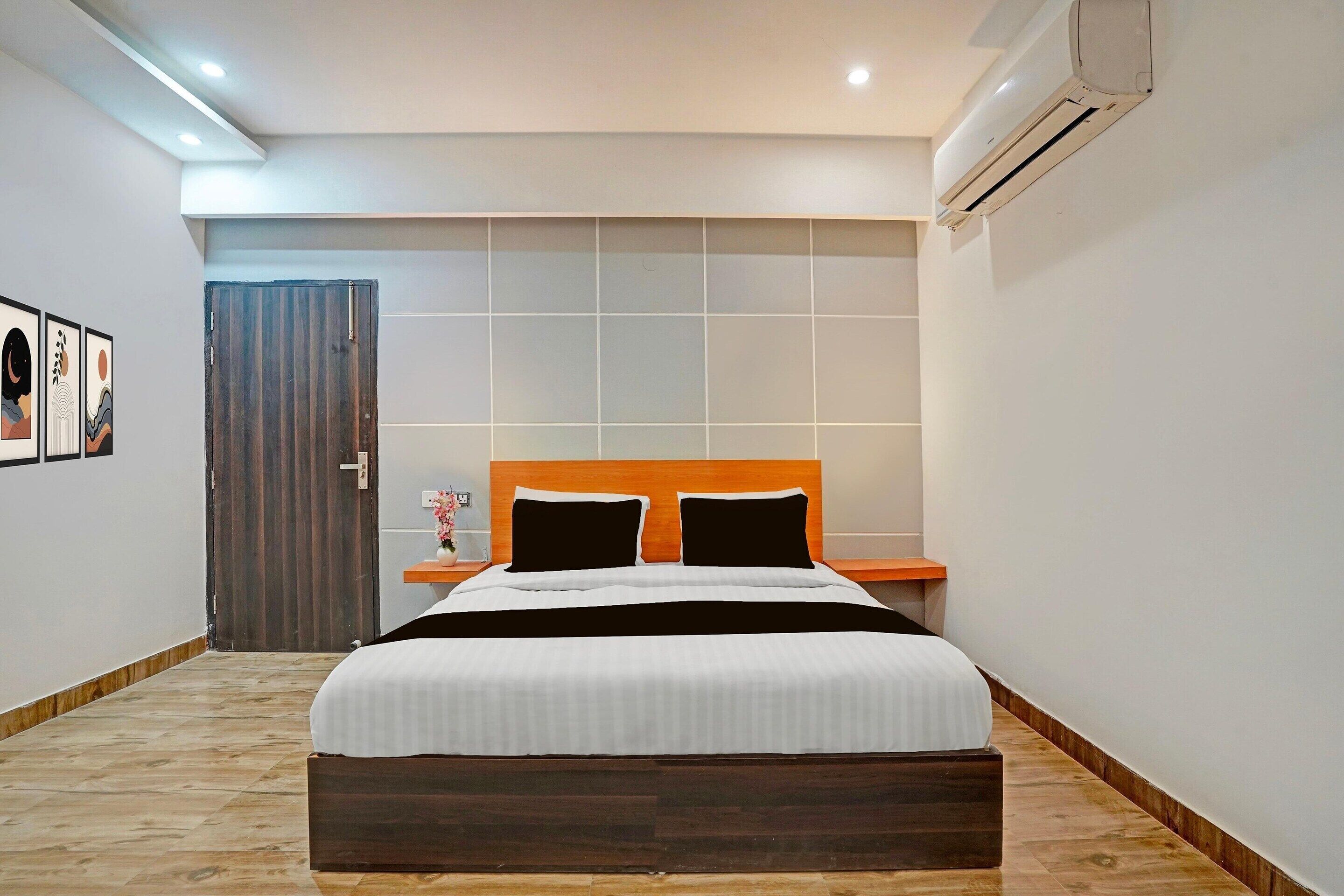 Une chambre à coucher comprenant un lit, une table de chevet, un climatiseur fixé au mur et une porte.