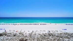 Ein Strand mit weißem Sand, klarem, blauem Wasser und wolkenlosem Himmel.
