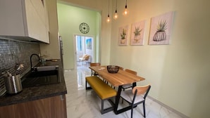 Una cocina con una mesa de madera, banco y sillas, un fregadero y un reloj en la pared.