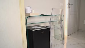 Habitación compacta con un refrigerador pequeño negro, un estante de vidrio y una estructura metálica.