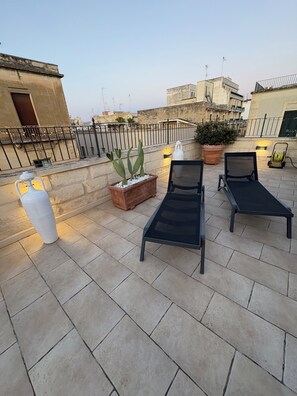 A rooftop terrace with two lounge chairs, a potted plant, and a decorative vase. - La Fitolacca B&B (Lecce)