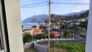 A coastal town with buildings, a road, and a view of the ocean. - Dino's Sea View (Porto da Cruz)