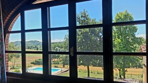 Ein Zimmer mit großen Fenstern und Blick auf einen Swimmingpool und die umliegende Landschaft.