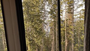 A room with a large window overlooking a snowy outdoor area with a wooden picnic table. - Praloup 1600 Studio ground floor with exterior (Uvernet-Fours)