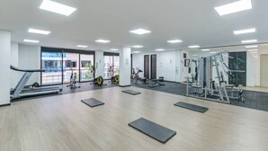 Une salle de sport équipée de matériel d’exercice, de tapis et de grandes fenêtres.