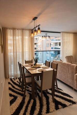 Un appartement moderne comprenant un coin repas, un canapé et une vue sur un immeuble.