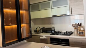 Une cuisine moderne dotée d’un îlot central, d’appareils électroménagers en acier inoxydable et d’un luminaire suspendu.
