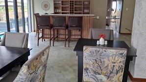 Un comedor con barra, sillas y aparador.