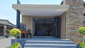 Una entrada moderna con fachada de piedra, una escalera que lleva a la entrada, y plantas en macetas a ambos lados.