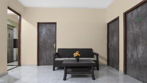 Eine Lobby mit einer Couch, einem Couchtisch mit Blumen und zwei Türen mit Nummern.