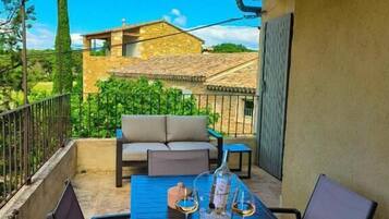A patio with a table set for two, outdoor seating, and a view of a stone building in the background.