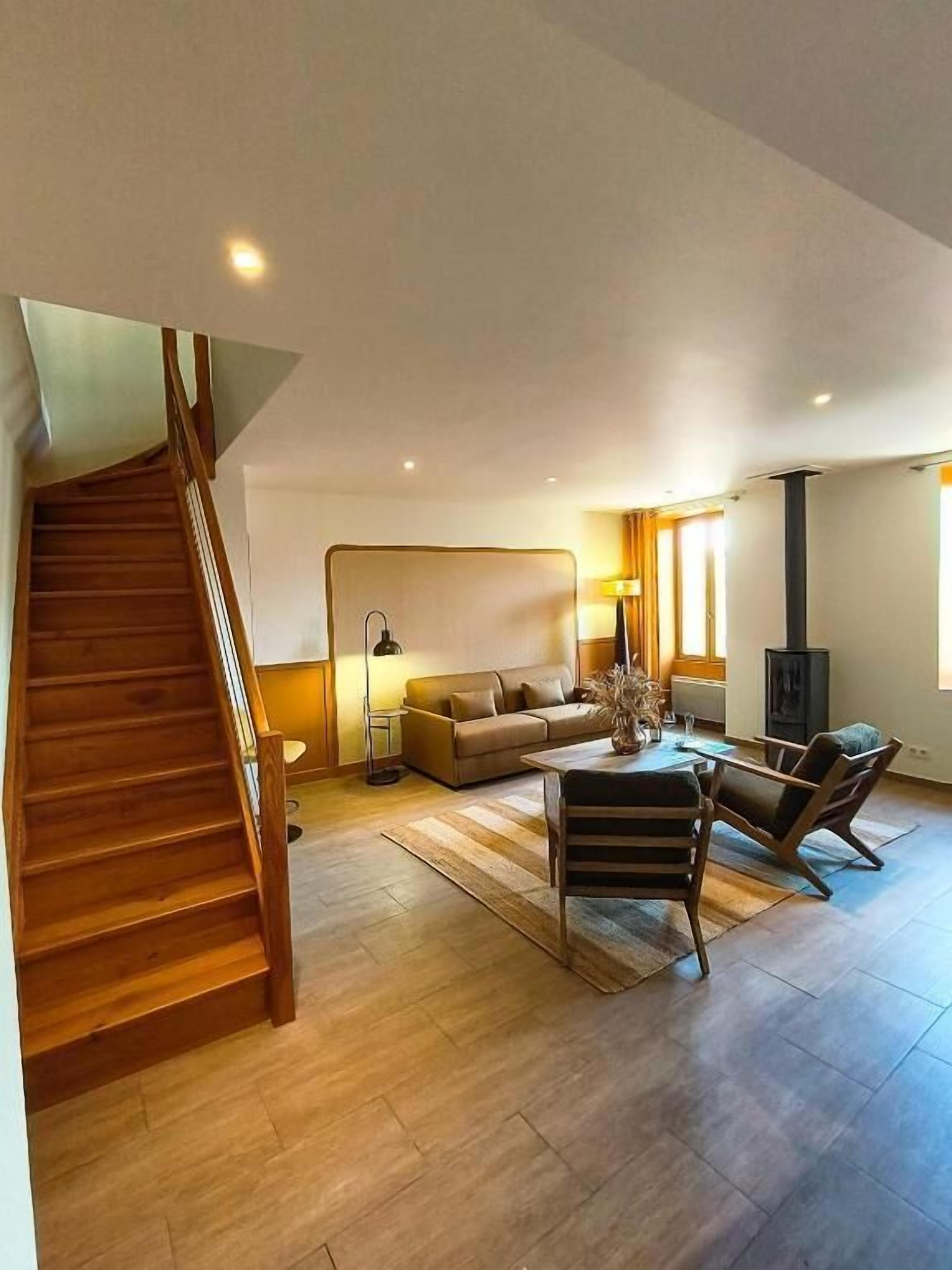 A modern living room with a wooden staircase, a sofa, a coffee table, and a fireplace.