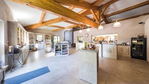 A spacious kitchen with wooden beams, a wine rack, and a central island. - Domaine de Montine - Chambres de Charme (Grignan)