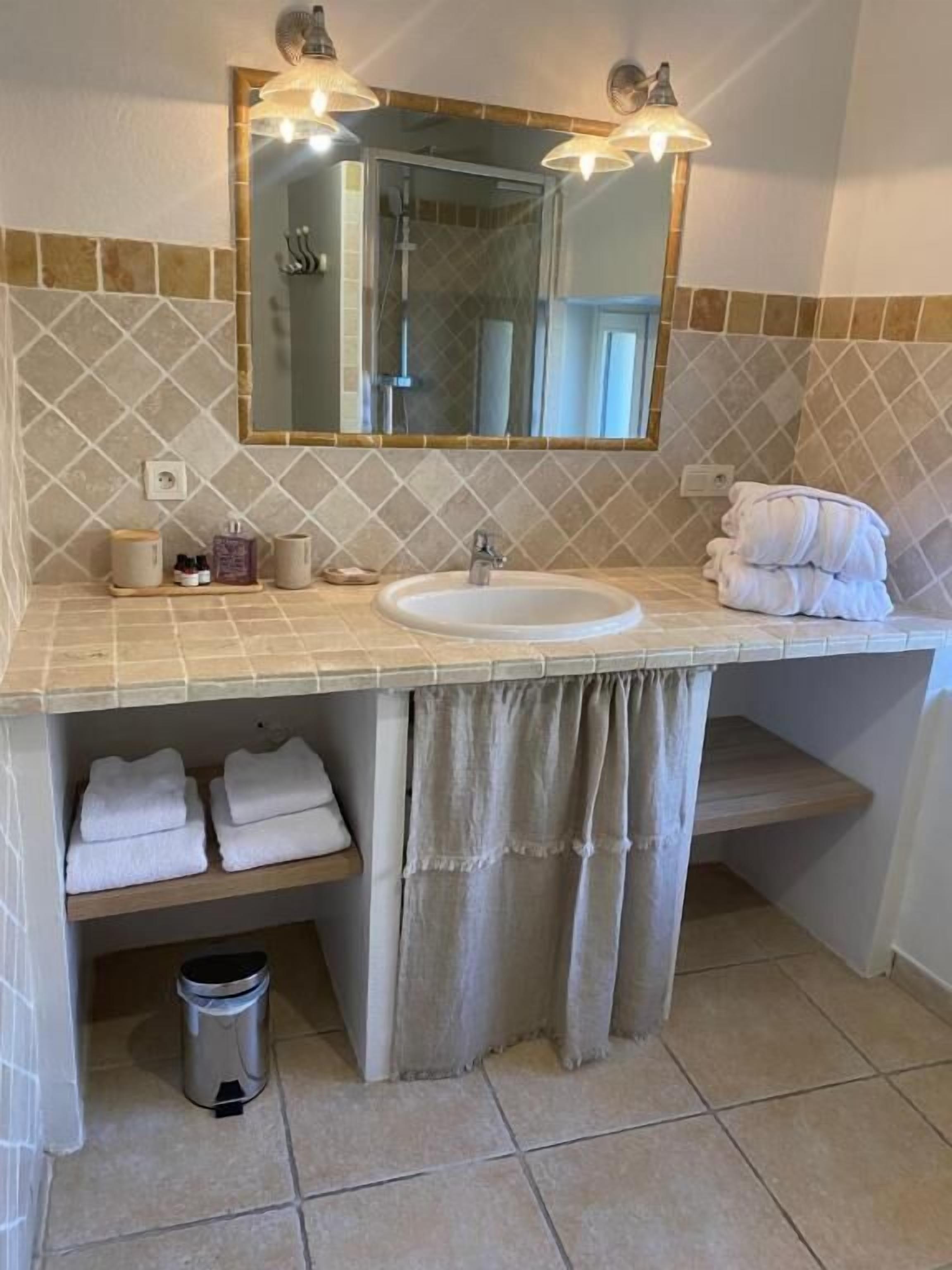 Ein Badezimmer mit Waschbecken, Spiegel, Handtuchhalter und Mülleimer.