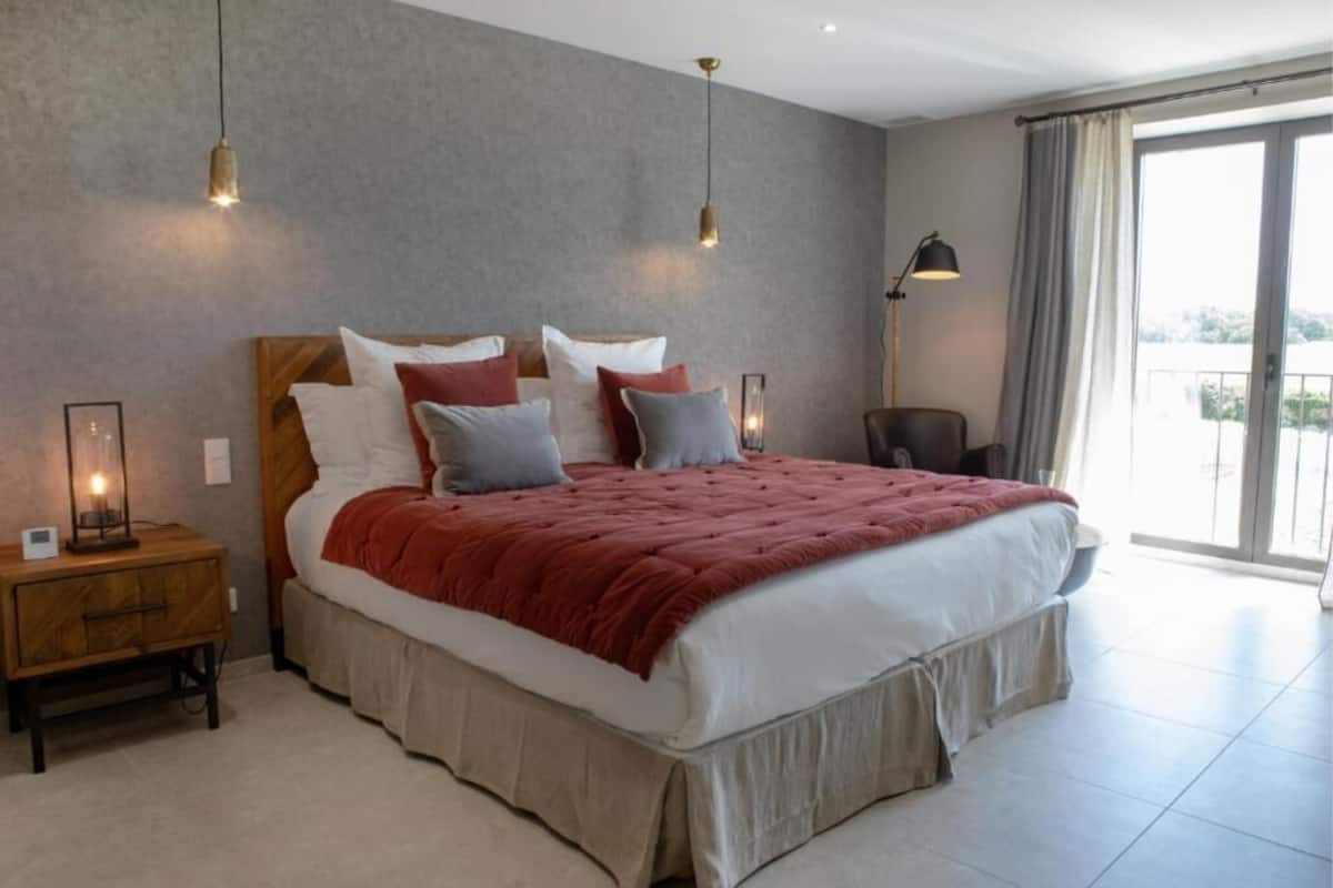 Una camera da letto con un letto grande, comodini, una lampada e vista sull'esterno.