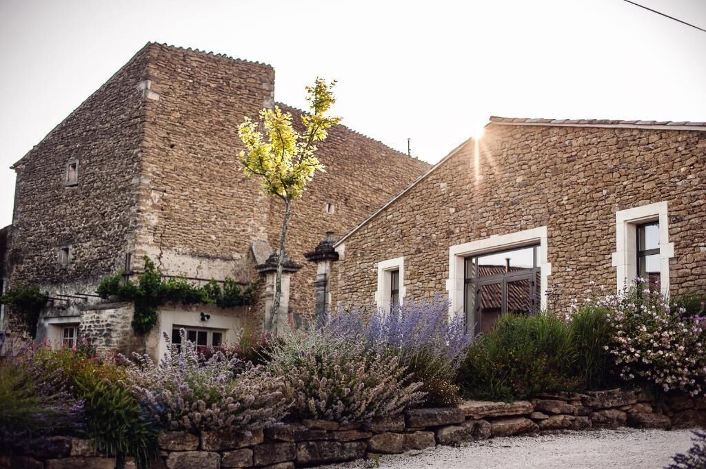 Een stenen gebouw met een traditionele architectuur, inclusief een opvallende toren en een verzorgde tuin met lavendel.