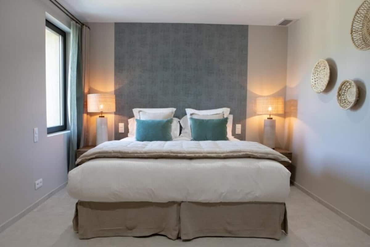Una camera da letto con un letto grande, due lampade sui comodini, una finestra con tende e decorazioni alle pareti.