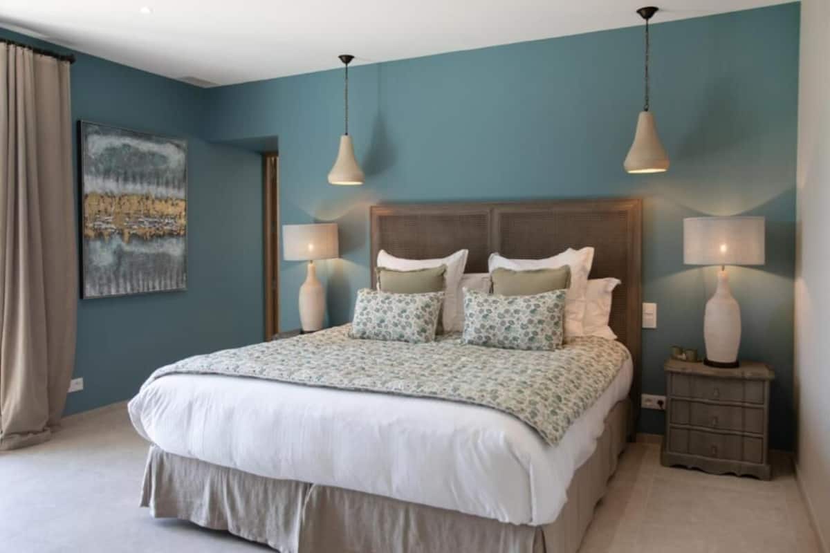 Una camera da letto con un letto grande, due lampade ai comodini, un comodino e un quadro appeso alla parete.