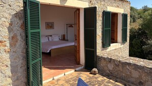 A stone building with a bed, open shutters, and a tiled floor. - Country House 'Fetget' with Mountain View, Private Pool and Wi-Fi (Illes Balears)
