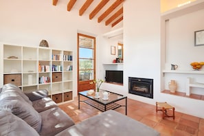 Una sala de estar con un sofá, una mesa de centro de vidrio, una chimenea y una estantería.
