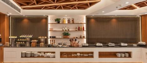 Una cocina moderna con vigas de madera en el techo, estantes empotrados con utensilios de cocina y una encimera con platos y cubiertos.