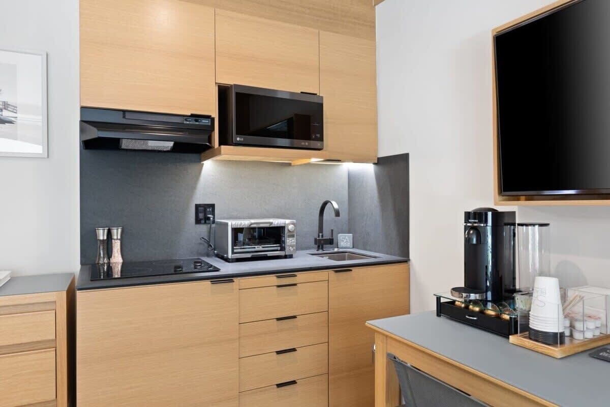 A compact kitchen with a microwave, toaster, sink, and coffee maker.