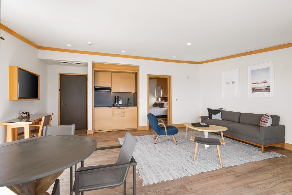 Una sala de estar moderna con una mesa de comedor, un sofá y una zona de cocina.