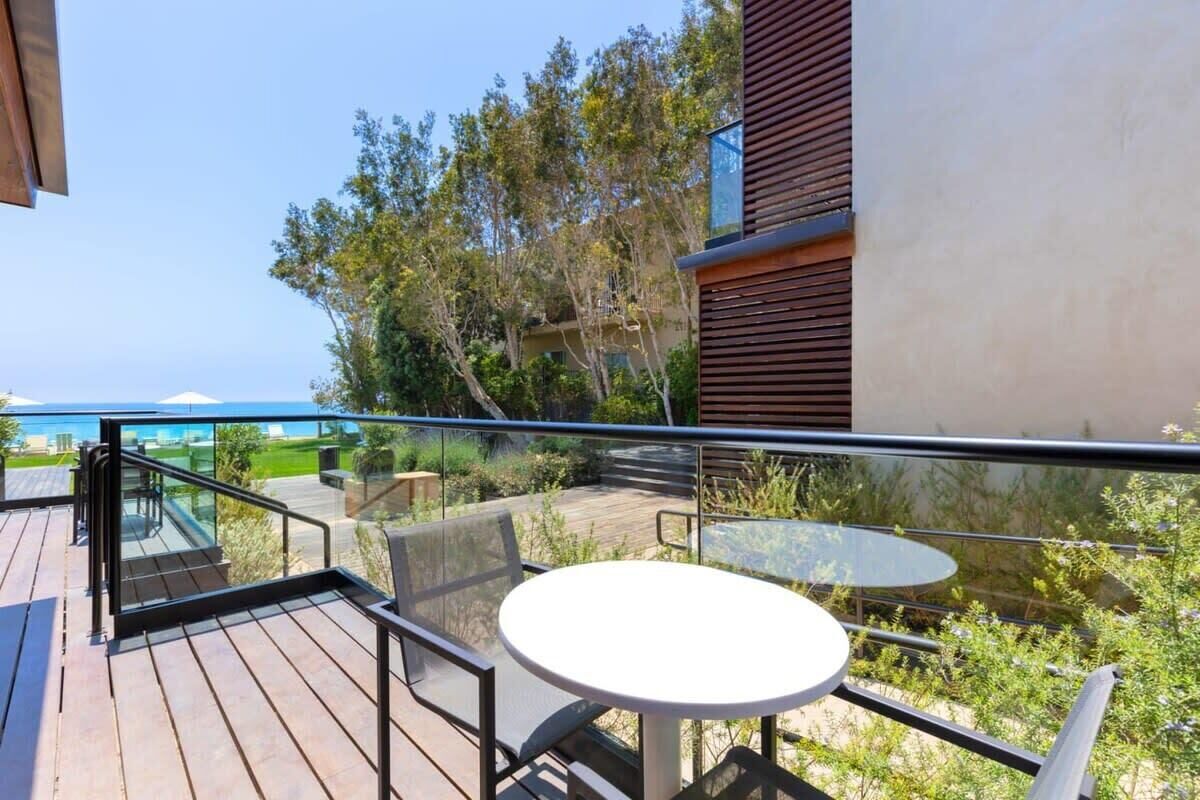 A balcony with a glass railing, a round table, and outdoor seating.