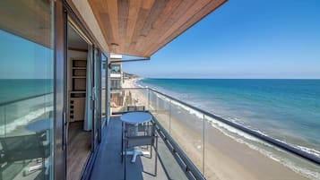 A balcony with a view of the beach and ocean.