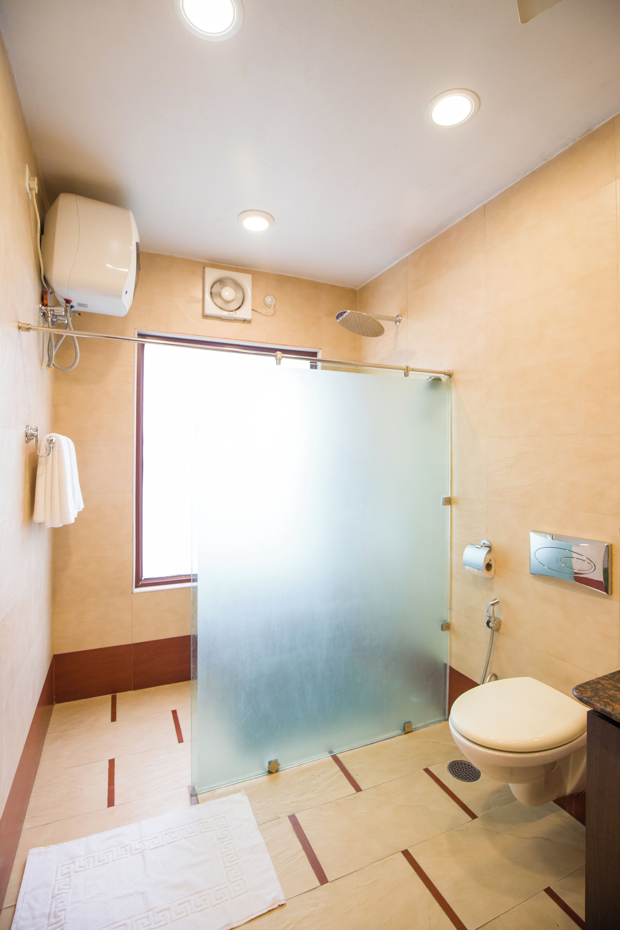 Een badkamer met een douchecabine van glas, een toilet en een handdoekrek.