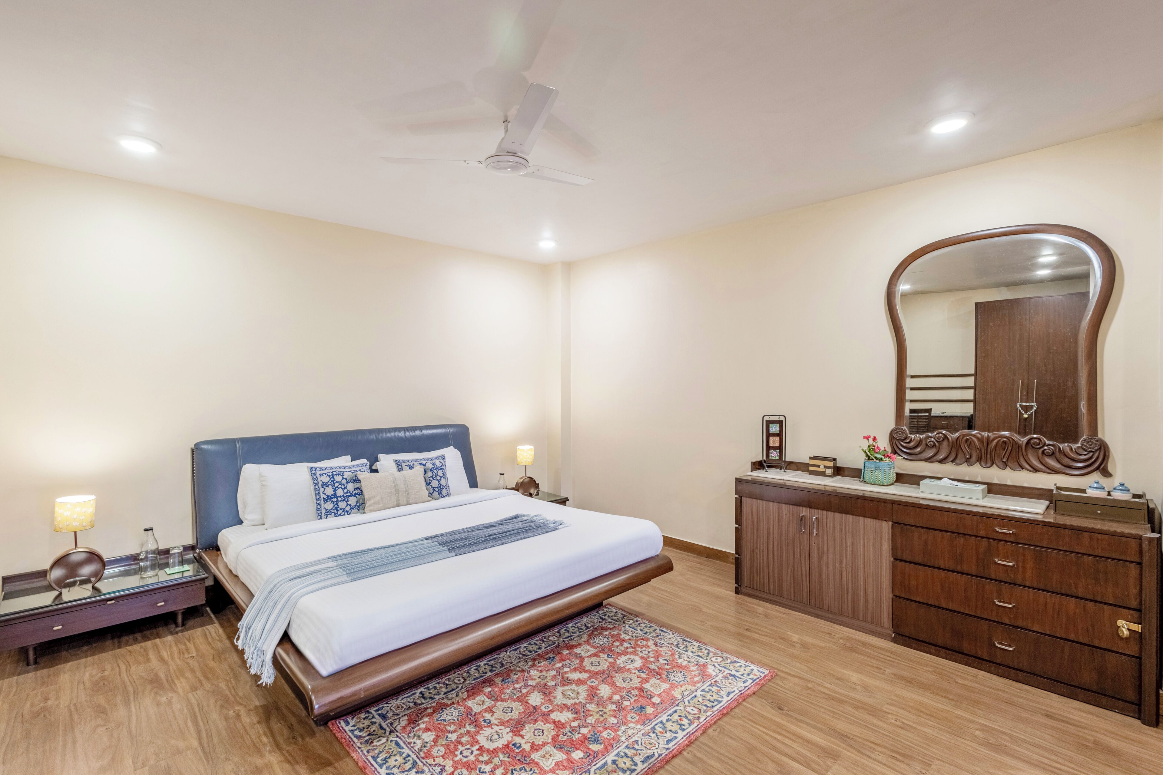 A bedroom with a bed, nightstands, a dresser, a mirror, and a ceiling fan.
