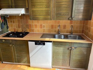 A compact kitchen with a dishwasher, double sink, and wooden cabinets. - Family house, direct beach access - 9 guests (Batz-sur-Mer)