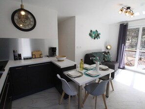 A modern kitchen with a dining area, a coffee machine, and a view of the outdoors. - Central apartment with parking - 4 guests (Bagnères-de-Luchon)