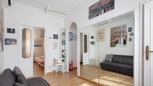 Una sala de estar moderna con un sofá, un separador de vidrio y una estantería.
