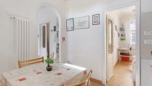 Un comedor con una mesa, sillas, una planta en maceta y cuadros en la pared.