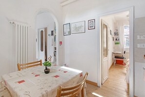 Ein Essbereich mit Tisch, Stühlen, einer Zimmerpflanze und gerahmten Bildern an der Wand.