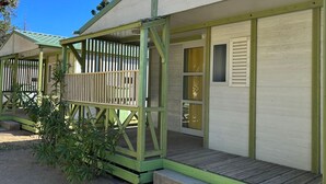 A row of cabins with a covered porch, a window with shutters, and a door.