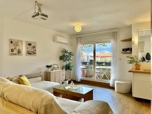 Ein modernes Wohnzimmer mit einer Couch, einem Couchtisch und einem Balkon mit Pflanzen.