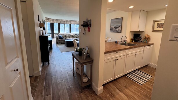A modern kitchen with white cabinets, a wooden countertop, and a view into the living area.