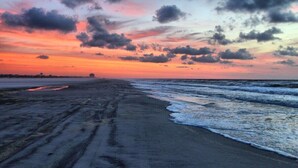 A beach with a sunset, waves, and a distant horizon.