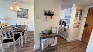 A modern kitchen with white cabinets, a wooden floor, and a dining area with a table and chairs.