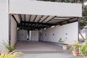 A covered outdoor area with a concrete floor, potted plants, and a metal roof structure. - Classic With Twin Bed Sairaj Lodging (Satara)