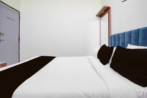 A bed with white bedding and black pillows, a blue headboard, and a white wardrobe. - Classic With Twin Bed Sairaj Lodging (Satara)